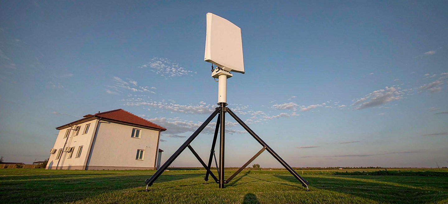 A freestanding Starlink stand set up on the grass of a rented house, with the building behind it completely untouched and no fixings anywhere